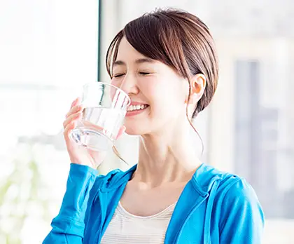 微笑みながらグラスの水を飲む女性